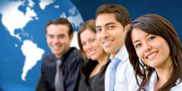 Four professionally dressed people are smiling and sitting in a row in front of a large world map. The focus is on the person at the front right, with others slightly blurred in the background. The map highlights business opportunities in Latin America, particularly around company formation.