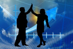 Silhouette of a man and a woman giving a high-five in front of a blue background with a rising arrow and graph lines, symbolizing success and growth, reminiscent of the dynamic economic progress seen in Mexico.