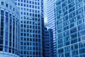 A cityscape in Mexico featuring multiple modern, high-rise office buildings with glass exteriors. The structures exhibit a mix of architectural styles with numerous windows and varying heights, all in shades of blue and gray, highlighting the region's commitment to sustainable development.