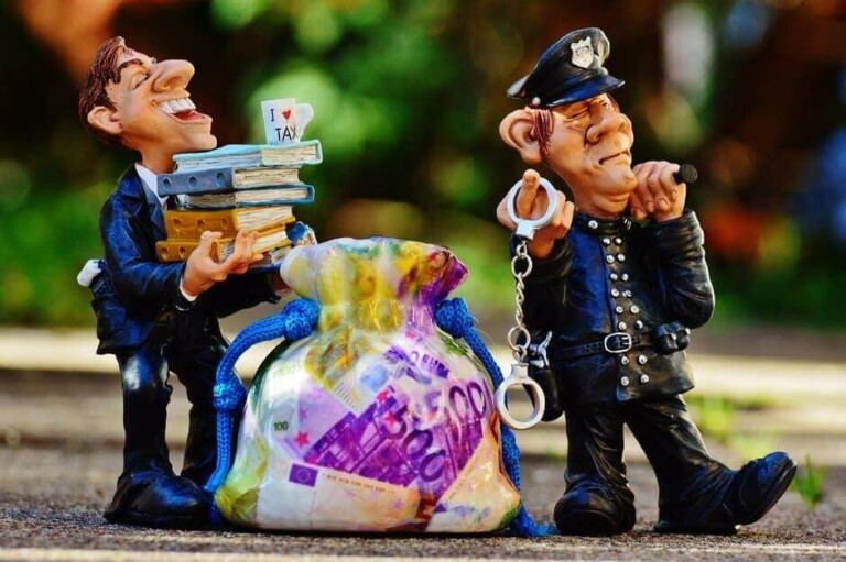 Una figura de un policía esposado se encuentra junto a otra figura de un hombre con una pila de libros y una taza con la etiqueta "I ♥ TAX". Entre ellos hay una bolsa llena de coloridos billetes en euros, que simboliza los integrales Servicios de Due Dilingence. El fondo es un verdor borroso.