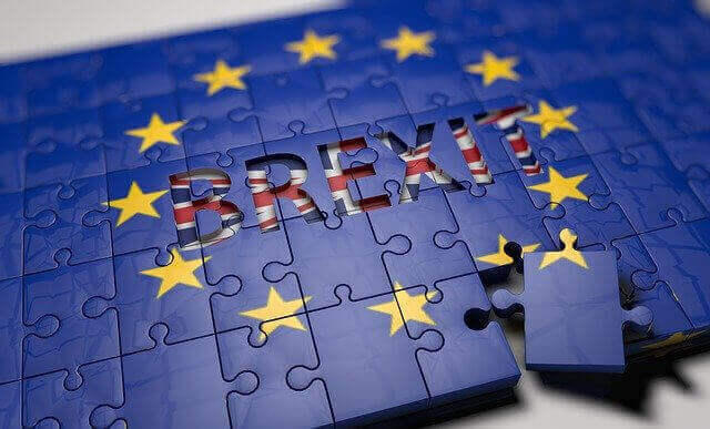 A jigsaw puzzle image depicts the European Union flag with the word "BREXIT" at the center in the United Kingdom's flag design. One puzzle piece is detached and placed to the side, symbolizing the UK's departure from the EU, as it starts a new trade dialogue with Latin America.