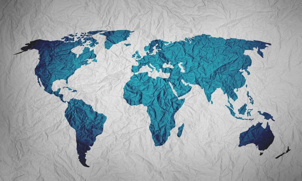 A world map displayed on a wrinkled, textured background evokes the feel of a crumpled paper. The continents, shaded in blue, and the white oceans create a striking contrast. This serves as an ideal backdrop for companies looking to hire staff in Latin America without a local company presence.