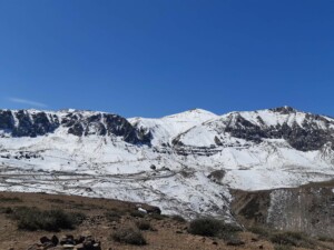 A snowy mountain range with a blue sky lies just outside Santiago de Chile, promoting sustainable tourism and contributing to economic growth.