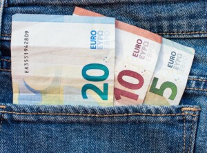 Three euro banknotes – a 20 euro note, a 10 euro note, and a 5 euro note – are partially visible sticking out of a denim jeans back pocket, much like the seed funding peeking out during the early stages of formação da empresa.