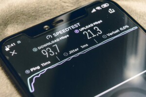 A smartphone screen displays an internet speed test result with a download speed of 93.7 Mbps, upload speed of 21.3 Mbps, and a ping of 11 ms. The time on the phone is 22:41. These speeds could greatly benefit Argentine businesses investing in Uruguay's digital landscape.