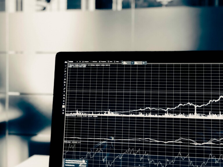 A close-up image of a computer screen displaying financial charts and graphs. The screen shows various line graphs with fluctuating data points against a grid background, suggesting analysis by fintech companies or economic trends in El Salvador's stock market performance.