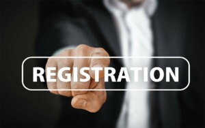 A person in a suit is pointing towards the camera, with a transparent rectangle overlaying the image bearing the words "Register a Trademark in Belize" in white capital letters. The background is blurred.