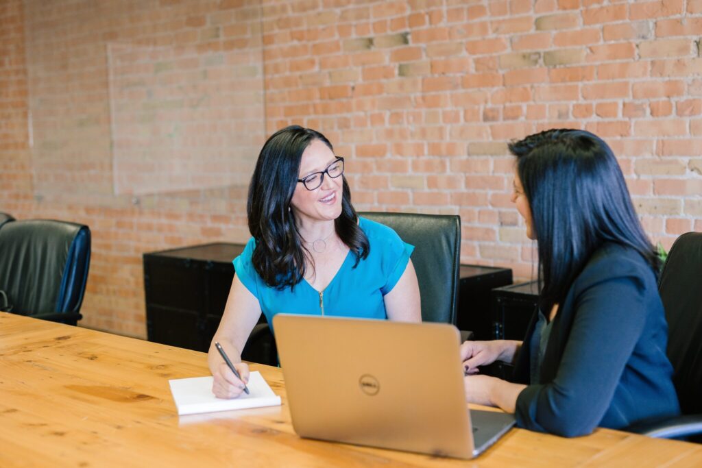 Two business women in an office discussing about corporate secretarial services in Chile. 