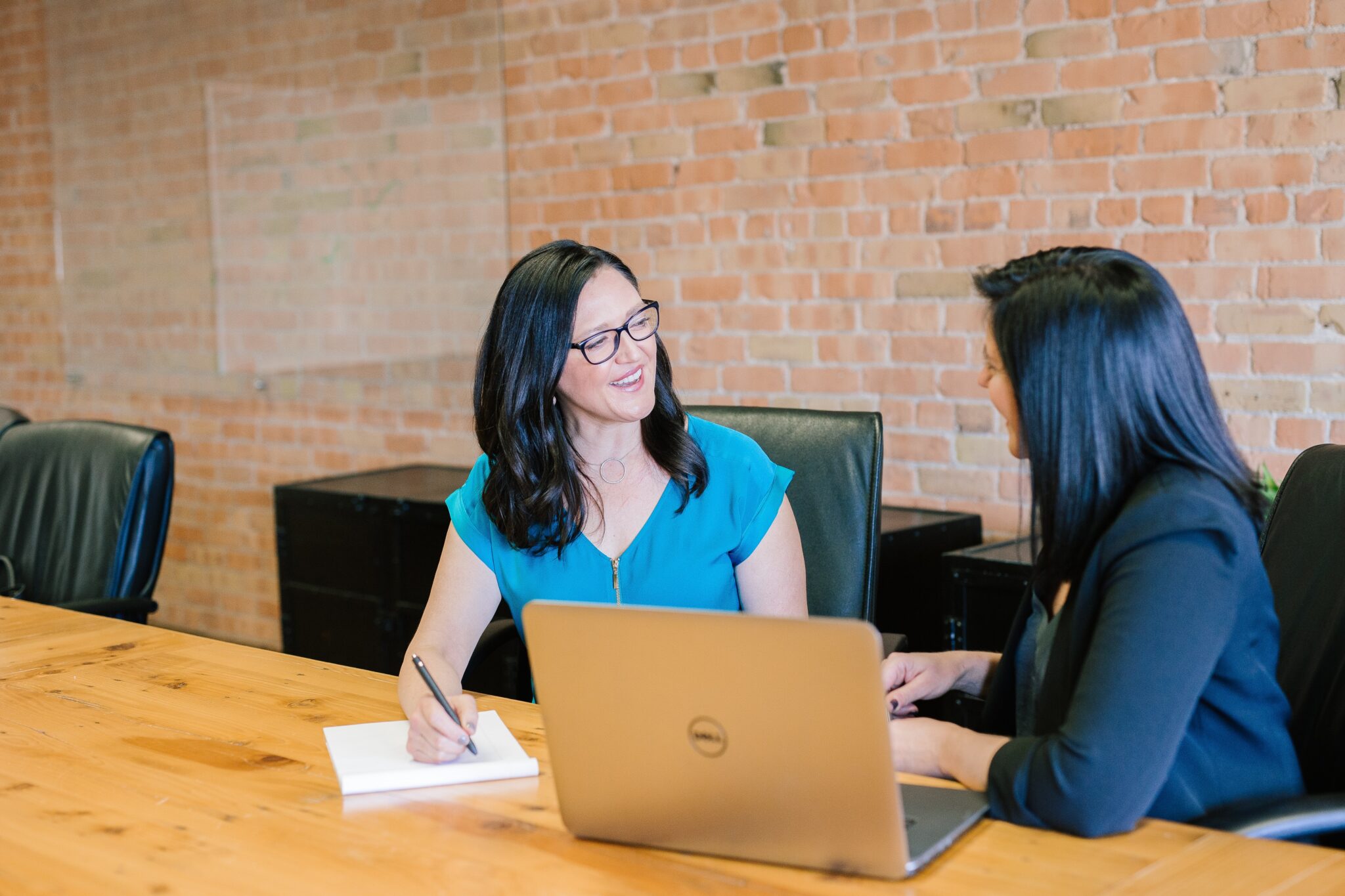 Two business women in an office discussing about corporate secretarial services in Chile.