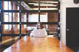 Woman sitting at the end of the table on her laptop searching about entity health check in Australia.  