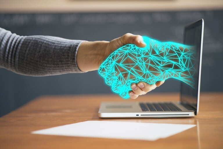 Man shaking hands with a virtual hand coming out of computer screen