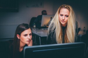 mujeres frente al computador realizando proceso debida diligencia de fusiones y adquisiciones en Colombia 