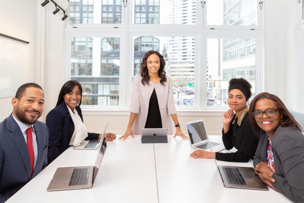 Five people sitting at a table with laptops