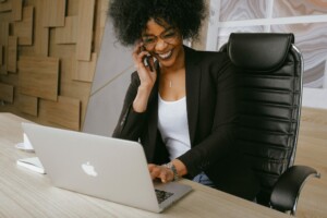 Una persona con gafas y una chaqueta negra sentada en un escritorio, hablando por teléfono y trabajando en una computadora portátil. El fondo presenta paneles de madera estampados y una taza blanca se coloca al lado de la computadora portátil. Parecen estar discutiendo los desafíos de hacer negocios en México.