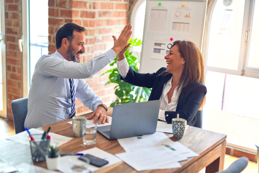 Two business executives in an office are high-fiving while talking about Ecuador's double taxation agreements