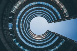 A view looking up at the interior of a multi-story modern building with circular balconies creating a spiral effect, much like the intricate work of an International Tax Accountant in Chile. An open blue sky is visible through the center.