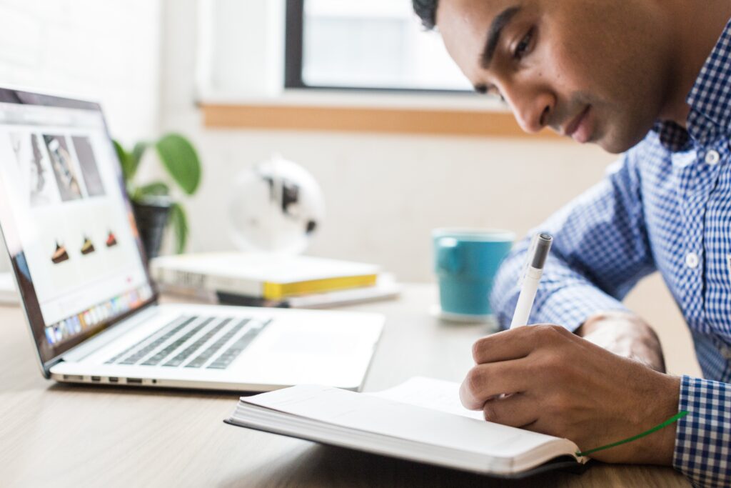 A man writing in a notebook, representing someone noting the steps to get a business visa in Brazil. 