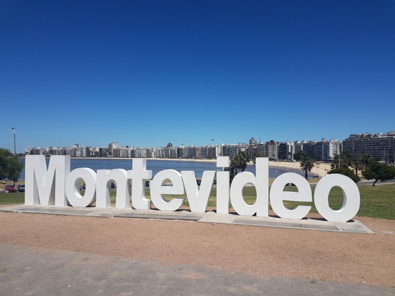 Large white letters spell out "Montevideo" in a park setting with a backdrop of city buildings and a clear, blue sky, embodying the vibrant spirit of Uruguay startups.