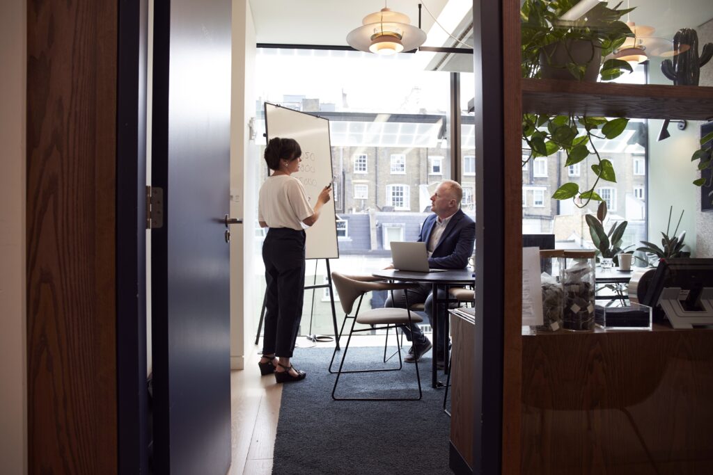 a businessman and a businesswoman in an office disuccing about the advantages of hiring a corporate legal counsel in Colombia.