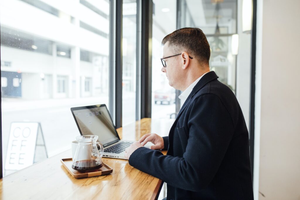 Businessman in a coffee shop in front of a computer, representing a corporate lawyer in the Dominican Republic.