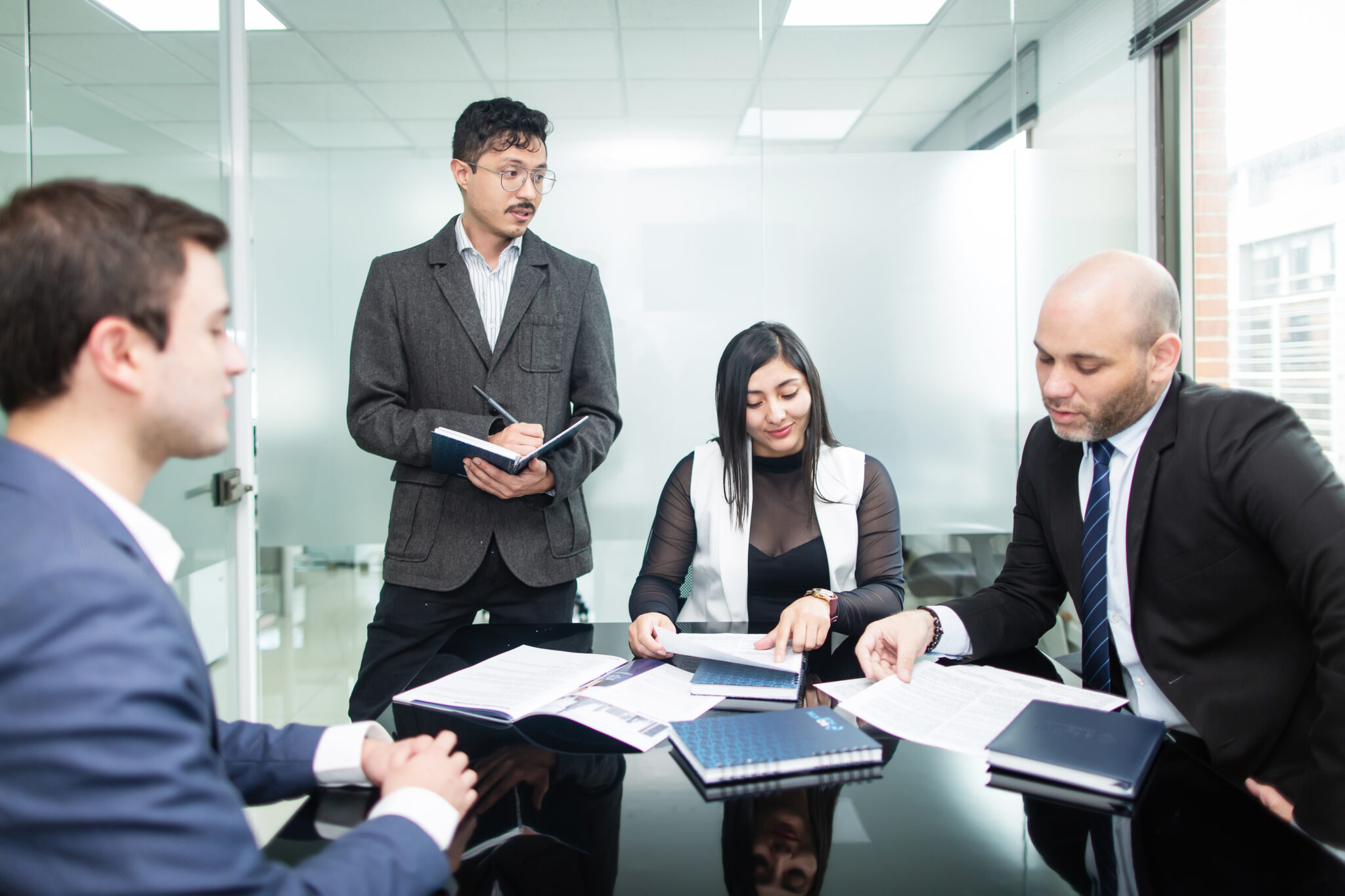 Cuatro empresarios en una oficina, representando a un grupo de personas que discuten sobre las ventajas de la diligencia debida en El Salvador. 