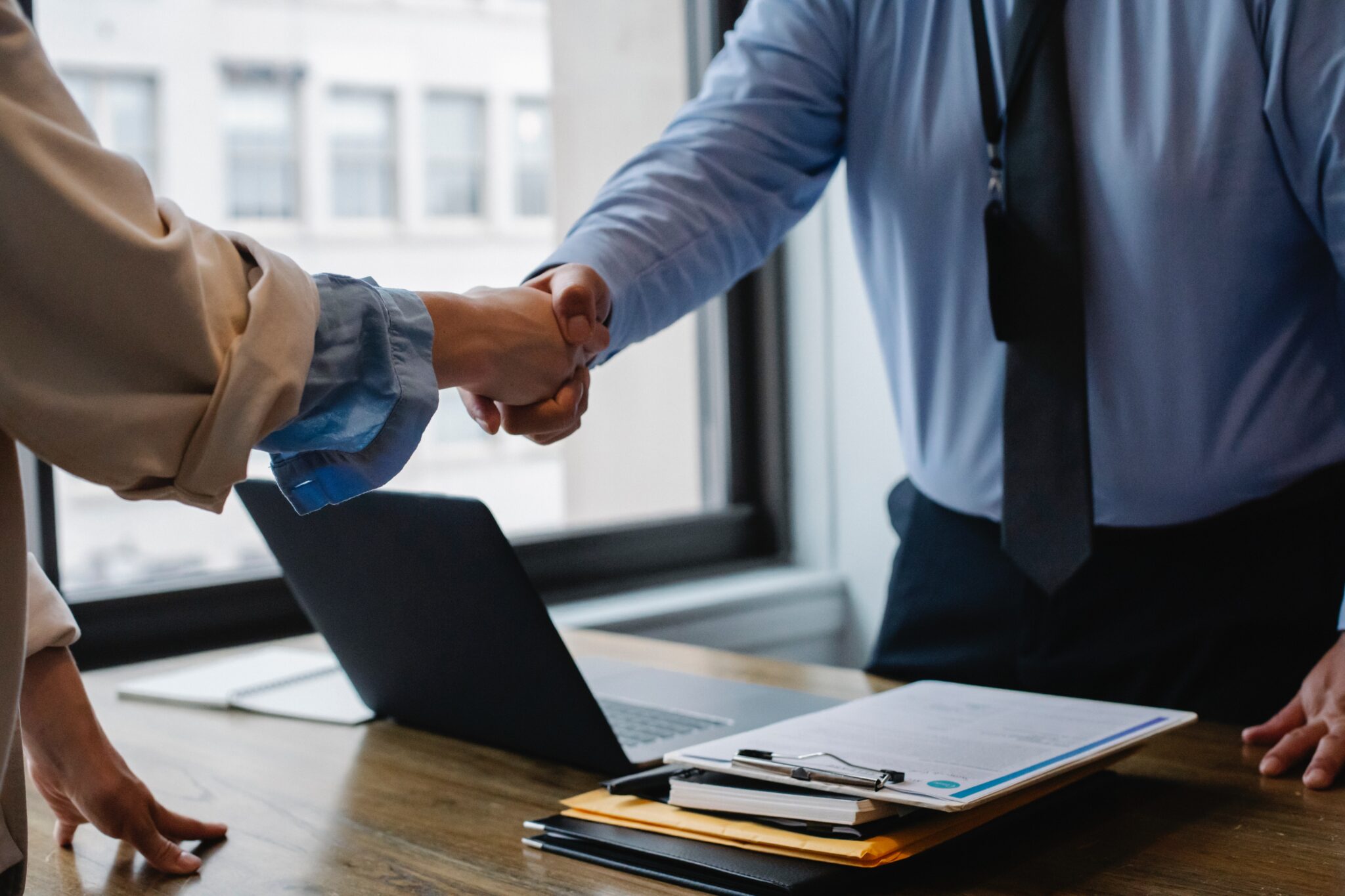 Two people shaking hands, representing a recruiter talking to a job candidate about their work history as part of a process for undertaking background checks in Peru