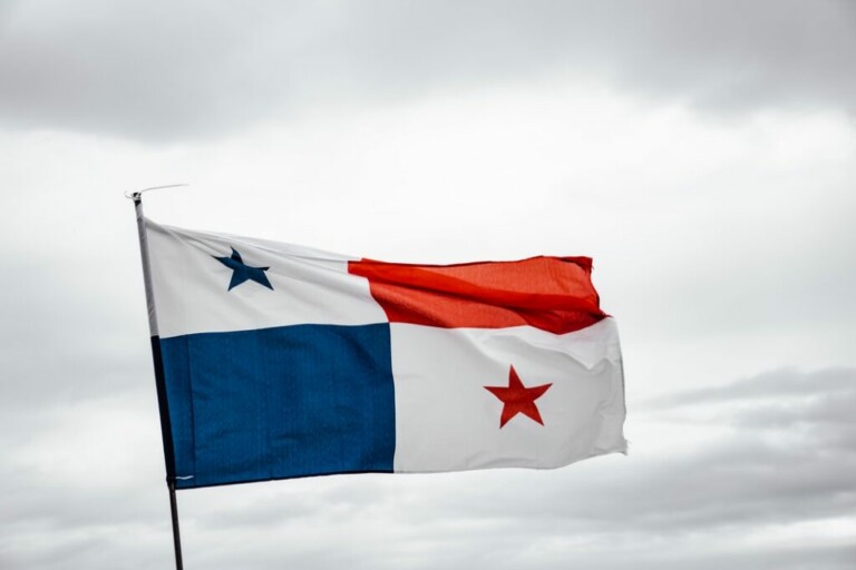 La imagen muestra la bandera de Panamá, con una división vertical con azul a la izquierda y rojo a la derecha. El cuadrante superior izquierdo tiene una estrella azul sobre un fondo blanco y el cuadrante inferior derecho tiene una estrella roja sobre un fondo blanco. Bajo este cielo nublado, la Visa de naciones amigas de Panamá de Panamá podría ser relevante para los viajeros.