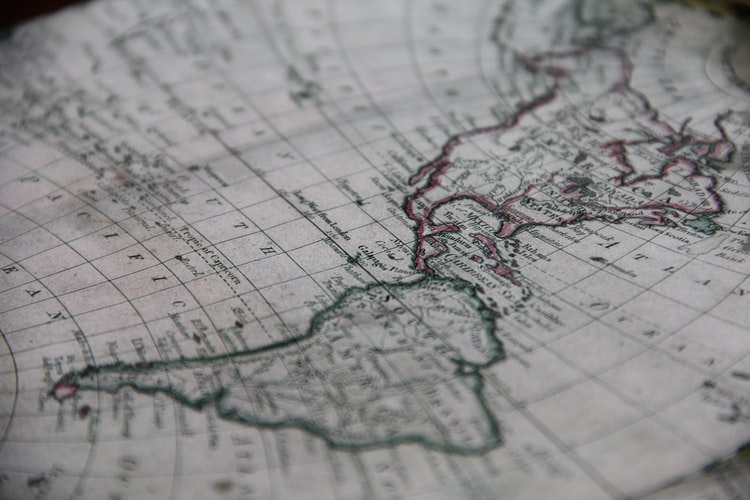 Una vista cercana de un mapa antiguo que muestra partes de América del Norte y del Sur. El mapa presenta detalles geográficos y fronteras delineadas en diferentes colores, con texto que etiqueta varias regiones y cuerpos de agua, incluidas áreas relevantes para negocios en América Latina. El mapa tiene un aspecto ligeramente envejecido y desgastado.