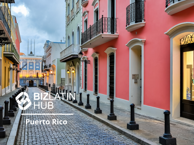 A narrow, cobblestone street in Puerto Rico flanked by colorful buildings with balconies. The street is bathed in evening light, perfectly capturing the charm of Puerto Rico tourism. The words "BizLatin Hub Puerto Rico" are overlaid on the left side of the image.