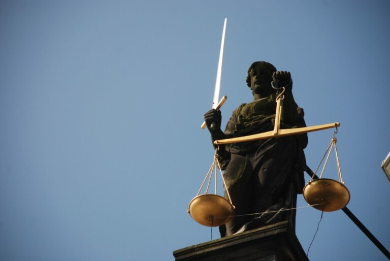 Estatua de Lady Justice sosteniendo una espada en su mano derecha y una balanza en su mano izquierda, contra un cielo azul claro, simbolizando los principios del Derecho Laboral México.