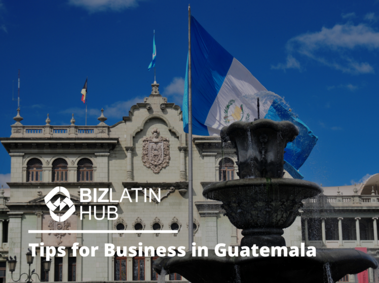 A historic building with flags flying on top is seen under a blue sky. The foreground features a stone fountain with water cascading down. The text overlay reads "BIZLATIN HUB Tips for Doing Business in Guatemala.