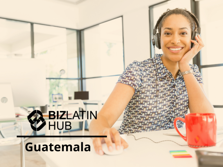 A woman with headphones is sitting at a desk, smiling, and using a computer mouse. There is a red mug and colorful sticky notes on the desk. Text on the image says "Biz Latin Hub Guatemala." The background shows a modern office with large windows as she navigates through labor obligations in Guatemala.