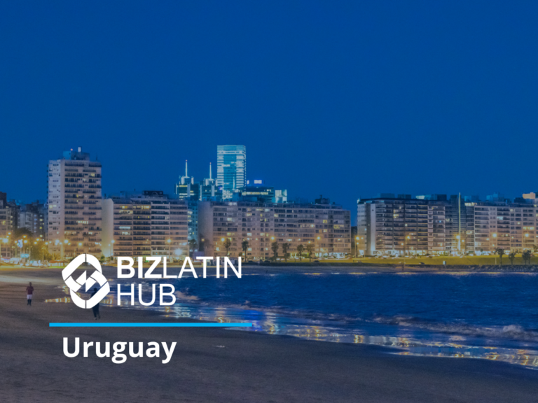 Una vista nocturna de una playa de la ciudad de Uruguay con edificios de gran altura iluminados al fondo. El logo de BizLatin Hub y la palabra "Uruguay" están superpuestos en la imagen.