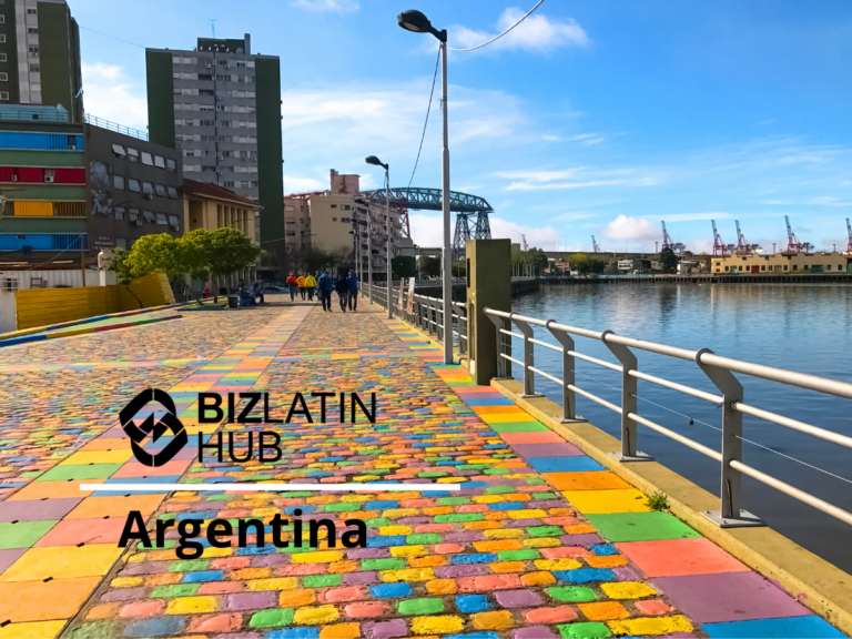 A vibrant waterfront area in Argentina with multi-colored tiled pavement and modern buildings in the background. Several people are walking along the waterfront near a body of water with industrial cranes visible in the distance. Text reads "Biz Latin Hub Argentina: your headhunter na Argentina.