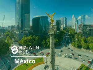 Wide-angle view of the Angel of Independence monument in Mexico City, with surrounding modern office buildings and a busy roundabout filled with traffic. The Biz Latin Hub logo and text "México" are overlaid on the bottom left corner of the image.