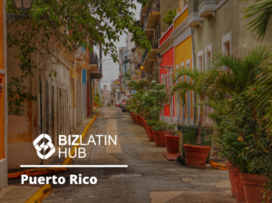 A narrow street in Puerto Rico lined with potted plants and colorful buildings on both sides showcases lush greenery and balconies overlooking the scene. The logo and text overlay read "BIZLATIN HUB Puerto Rico," with insights on leis trabalhistas em Porto Rico.