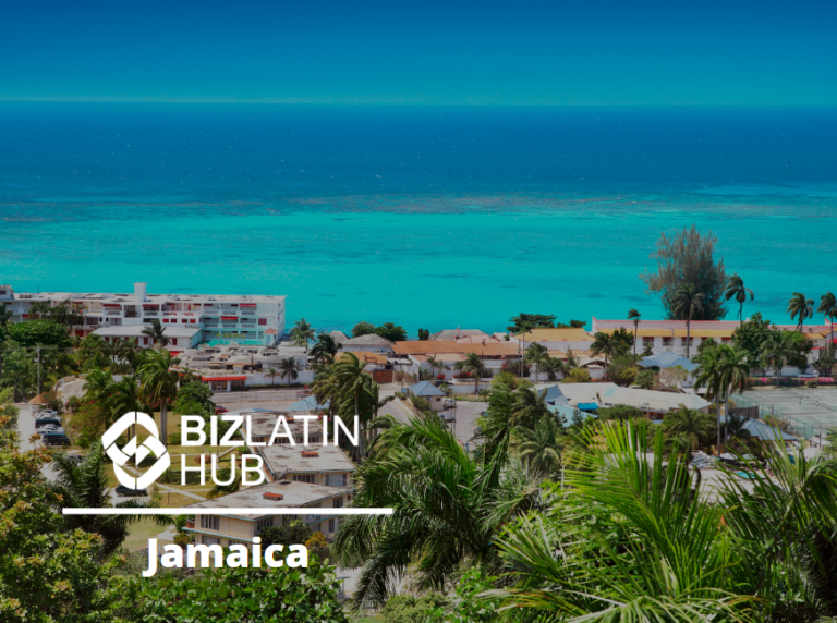 A coastal cityscape with numerous buildings nestled among lush green trees. The turquoise sea extends to the horizon under a clear blue sky. Text on the image reads "Biz Latin Hub" and "Formação de empresa na Jamaica.